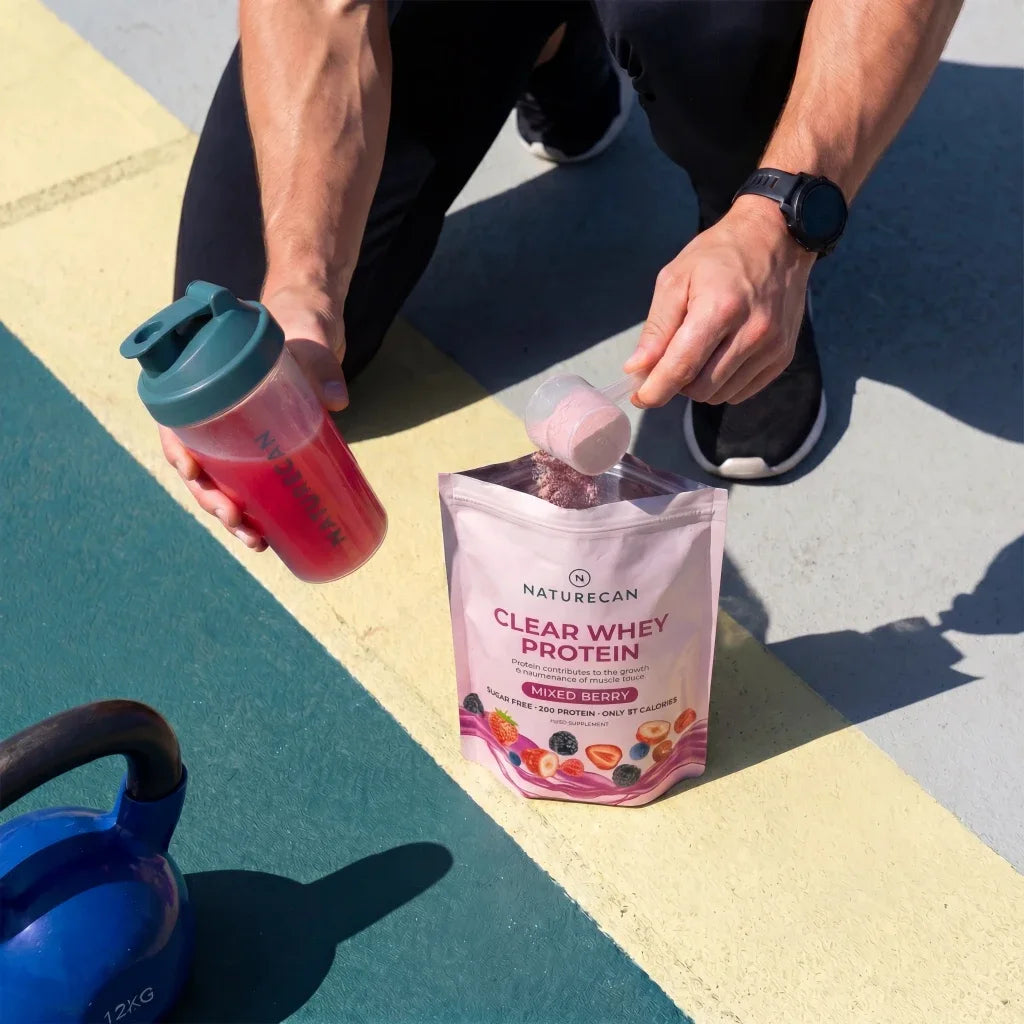 Clear Whey Protein Naturecan o smaku owoców leśnych z shakerem i miarką białka po treningu